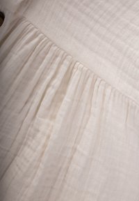 Weiße, leichte Stoff mit einer weichen, strukturierten Oberfläche. Verfügt über ein gerafftes Design mit Falten und einem geraden Saum.