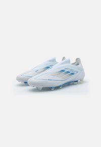 Ghete de fotbal albe cu un design elegant și accente albastre. Fabricate dintr-un material ușor, având o textură netedă și multiple crampoane pentru aderență.