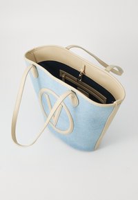 Gaiši zila auduma somiņa ar beidzīgu ādas akcentu, kurai ir liels 'V' logotips un iekšējā kabata ar rāvējslēdzēju.