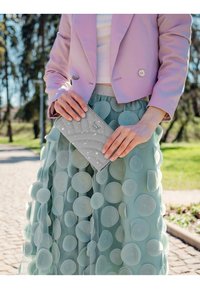 Light purple cropped blazer, white top, layered mint green skirt with circular fabric accents, and a light gray zippered clutch with white details.