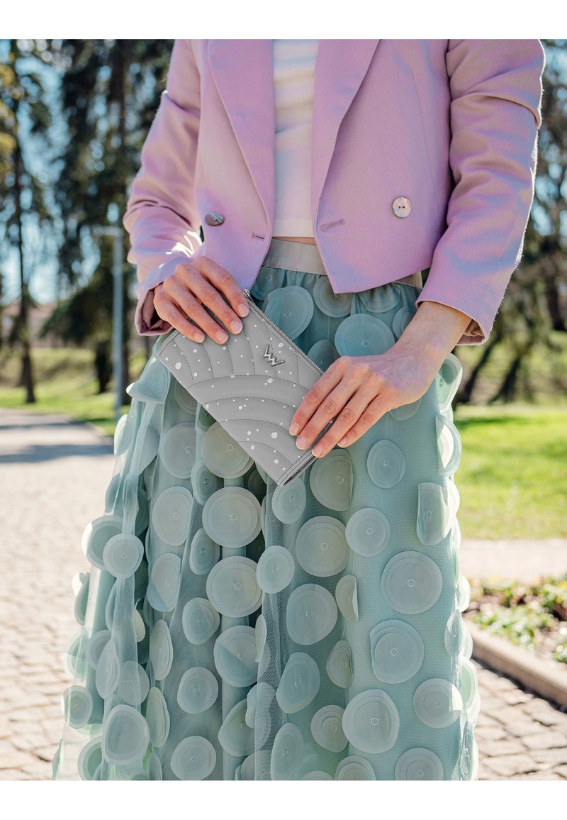 Light purple cropped blazer, white top, layered mint green skirt with circular fabric accents, and a light gray zippered clutch with white details.