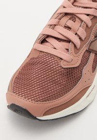 Brune netting sneakers med rosa skinnakenter, sekskantet mønster på overdelen, flate snørebånd, polstret såle og teksturert gummiyttersåle.