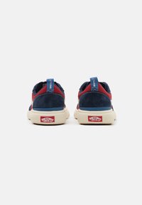 Sneaker blu navy e rosse con tomaia in suede, suola grigia chiara e accenti rossi con il marchio sul tallone e sulla linguetta.