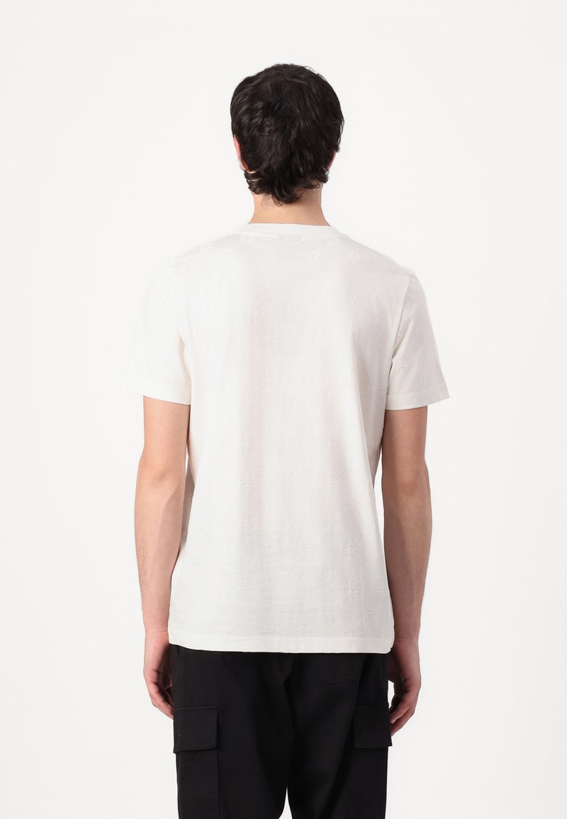 Weißes Baumwoll-T-Shirt mit Rundhalsausschnitt, das dezente strukturierte Muster auf dem Rücken aufweist. Kurze Ärmel und lässige Passform.
