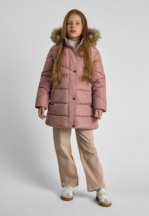 Rosa vadderad jacka med huva av konstpäls, knappstängning och quiltad textur. Matchas med beige vida byxor och vita sneakers.