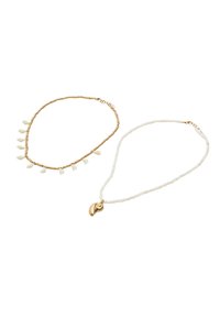 Złota naszyjnik z koralików z białymi akcentami w kształcie kropli, a także drugi naszyjnik z białych koralików z zawieszką w kształcie złotej muszli.