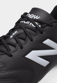 Svart New Balance-sneaker med svarte lisser, hvit "N"-logo på siden og "442" trykt nær bunnen av lissene.