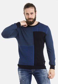 Blauer Strickpullover mit strukturierten Mustern, kontrastierenden unifarbenen und karierten Paneelen sowie gerippten Bündchen und Saum.