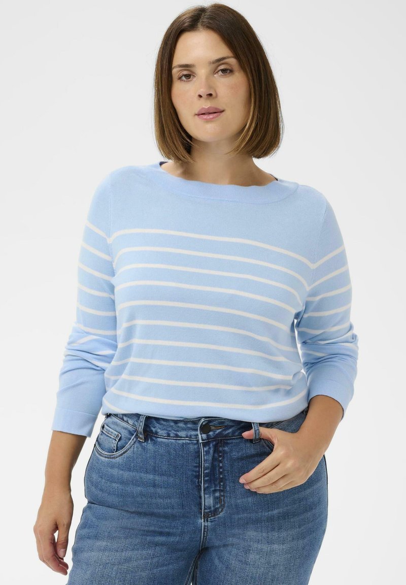 Pull bleu clair à rayures horizontales blanches avec un col rond, associé à un jean bleu taille haute. Texture douce et coupe décontractée.