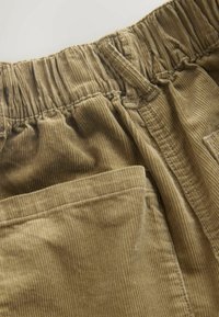 Corduroy shorts in a muted brown color, featuring a gathered elastic waistband, a patch pocket, and textured vertical lines.
