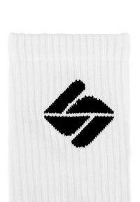 Weiße gerippte Socken mit einem schwarzen Logo, das zwei stilisierte Formen in der Art von Pfeilen oder Chevrons zeigt, die sich nahe der Oberkante befinden.