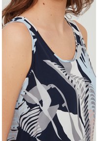Blusa sin mangas con fondo azul marino y patrones abstractos de flores y rayas en azul claro, gris y blanco. Tejido suave y ligero.