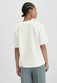 Witte katoenen T-shirt met korte mouwen, losse pasvorm en ronde halslijn. Eenvoudig ontwerp zonder patronen of extra accenten.