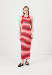 Robe débardeur rayée rouge et blanche, design ajusté, longueur genou, en mélange de coton, accompagnée de ballerines noires à bout pointu, texture lisse.