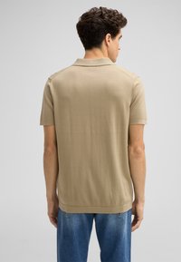 Beige polo shirt met korte mouwen en een rechte zoom, gebreide textuur en een klassieke kraag. Draag het met blauwe denim jeans.