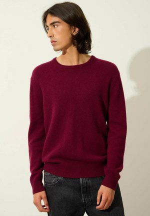 Bordeaux gebreide trui met een ronde hals, geribde manchetten en zoom. Zachte textuur, comfortabele pasvorm, te combineren met donkere jeans.