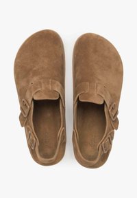 Brown suede sandals with two adjustable buckles, open-toe design, and textured footbed. Features a simple, curved shape and flat sole.
