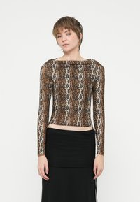 Camisola de mangas compridas com estampa de leopardo, com decote barco e design ajustado, feita de um tecido liso e elástico; combinada com uma saia preta.