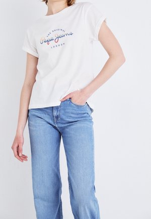 Biała bawełniana koszulka z podwiniętymi rękawami, z kolorowym napisem "Pepe Jeans London". Noszona z jasnoniebieskimi jeansami.