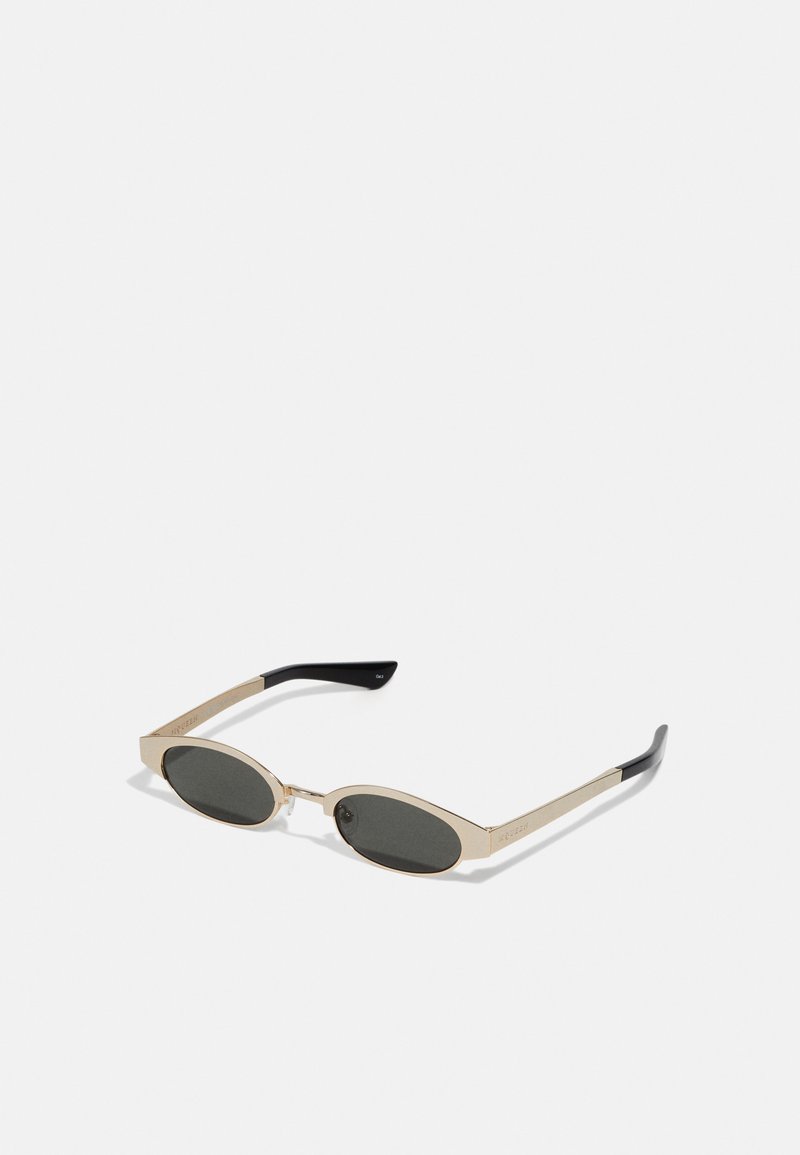 Sunglasses with an elongated oval design, gold metal frame, dark gray lenses, and black temple accents. Textured arms with branding detail.