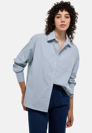 Chemise à rayures bleu clair et blanche, à manches longues et avec une poche sur la poitrine. Fabriquée en tissu léger avec une coupe décontractée.