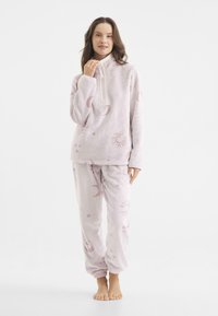 Conjunto de loungewear de fleece de color rosa claro que incluye un pulóver con cremallera y pantalones con cinturilla elástica, adornado con patrones de sol y luna.