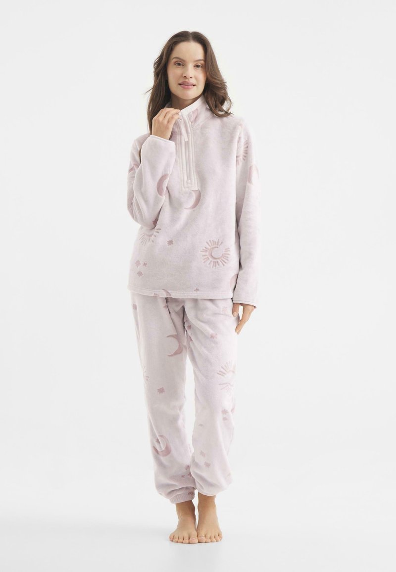 Conjunto de loungewear de fleece de color rosa claro que incluye un pulóver con cremallera y pantalones con cinturilla elástica, adornado con patrones de sol y luna.