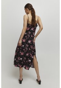 Rochie maxi neagră cu flori roz și albe, curele subțiri ajustabile, fente laterale și un design fluid.