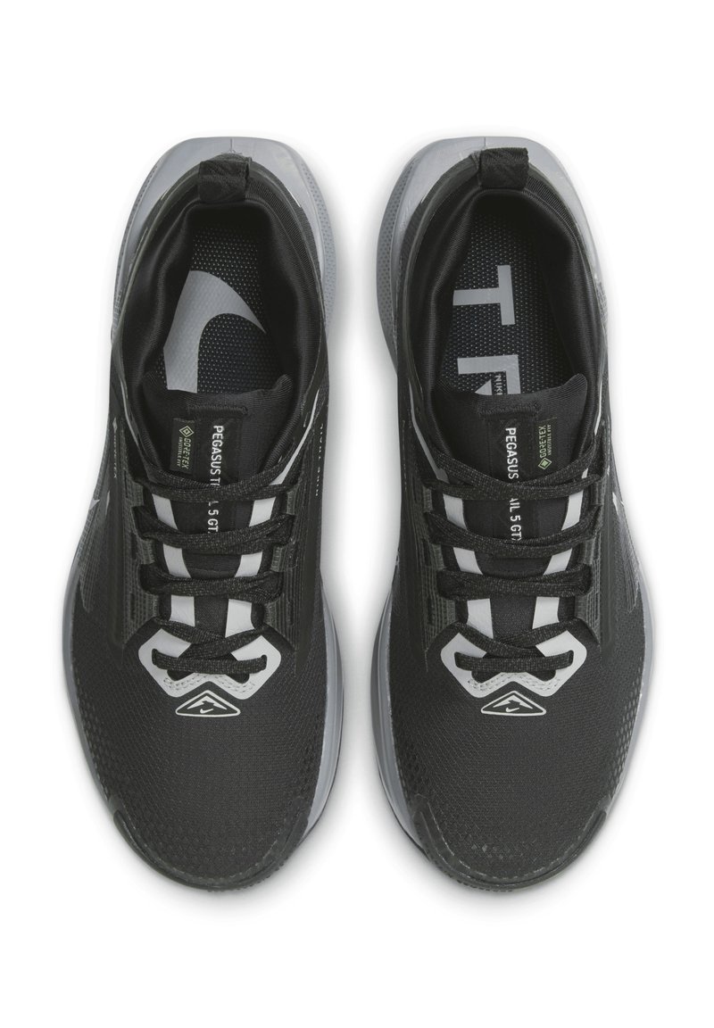 Zapatillas deportivas negras con parte superior de malla, detalles estructurados, acentos reflectantes y cordones negros; cuentan con una suela texturizada y un logotipo impreso en el interior.