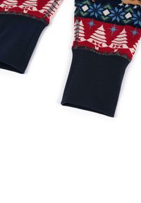 Puños de suéter en rojo y azul marino con un diseño estampado que presenta árboles blancos, copos de nieve y motivos de animales; textura acanalada en la tela azul marino.