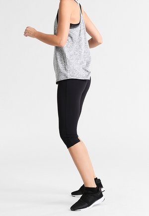 Top in tessuto grigio sportivo e leggings neri a tre quarti, caratterizzati da un tessuto morbido, un design aderente e scarpe da ginnastica nere con dettagli testurizzati.