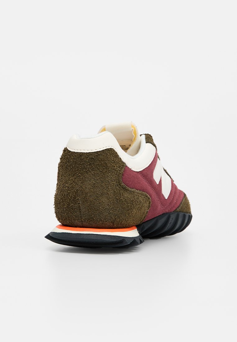 Zapatillas de ante y malla con un upper en color marrón y verde oliva, acento de logo blanco y suela de goma negra con una franja naranja.