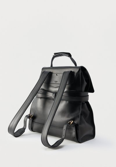 Μαύρο δερμάτινο σακίδιο με ρυθμιζόμενους ιμάντες, επάνω χερούλι και κλείσιμο με καπάκι, παρουσίαση σε λευκό απλό φόντο.