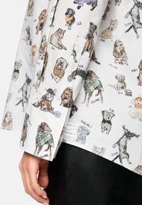 White button-up shirt featuring a playful pattern of various dogs, with detailed illustrations in a range of colors on a smooth fabric.