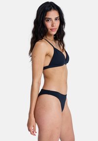 Ensemble bikini noir comprenant un haut triangulaire à fines bretelles et un bas taille basse assorti, tous deux en tissu lisse et extensible.