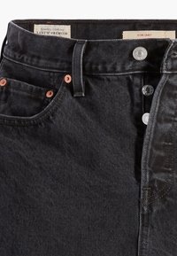 Donkerdenim rok met een knopenfly, voorzien van koperen klinknagels, voorkzakken en een merketiket aan de binnenkant van de tailleband.