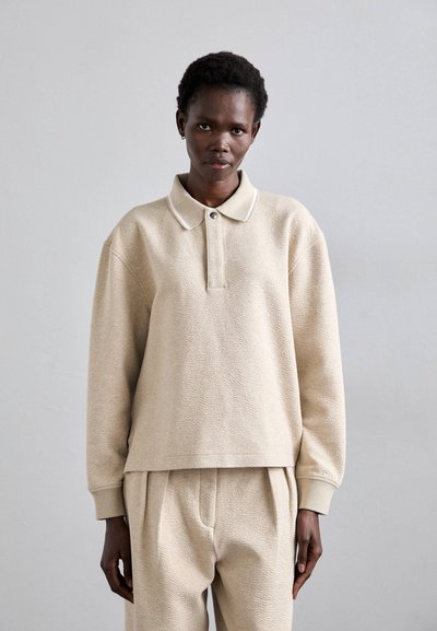 Beige fleece polo sweatshirt med en struktureret krave, knapdetaljer og ribstrikkede manchetter, parret med matchende fleecebukser.