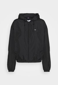 Zwarte, lichte capuchonjack met een rits aan de voorkant, elastische manchetten en een klein logo detail op de borst. Glad, mat oppervlak.