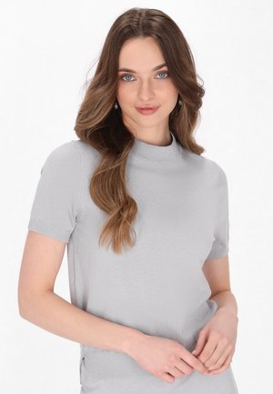 Hellgrauer, kurzärmeliger Oberteil mit hohem Kragen und gerippten Bündchen. Weicher Stoff mit einem subtilen Glanz und seitlichen Schlitzen für mehr Bewegungsfreiheit.