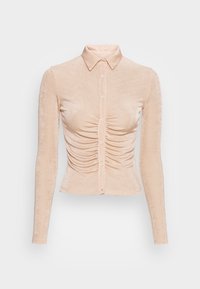 Ljus persikofärgad långärmad skjorta med krage, full knappstängning och rynkdetaljer längs torso. Mjuk och slät textur.