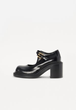 Schwarze Lackleder-Mary-Jane-Schuhe mit offener Zehe, seitlichem Schnallenverschluss und blockartigem Absatz. Glatte Textur und abgerundete Form.