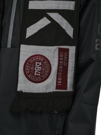 Écharpe noire et blanche avec des formes géométriques blanches, logo circulaire rouge D&U, texte « HATLO 1881 897261981 », drapée sur une manche de veste sombre.