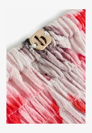 Elastinga medžiaga rožinių ir raudonų atspalvių, centre sukvadratinis auksinis metalinis užsegimas su stilizuotu „B“ logotipu. Tekstūruotas ir susmulkintas dizainas.