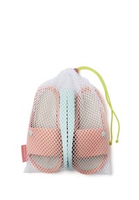 Zapatos de lona naranja en una bolsa de almacenamiento de malla blanca con un acento verde menta y un cordón amarillo. Presentan una plantilla texturizada y un detalle de logo.