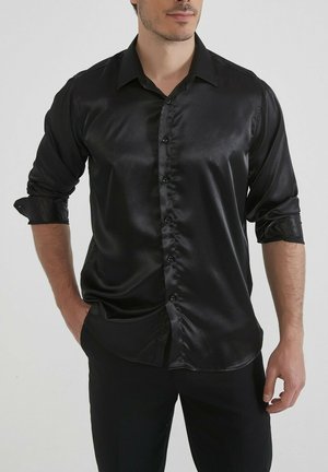 Chemise en satin noir avec un col classique, manches longues retroussées et un design à boutons sur le devant. Texture lisse et coupe ajustée.