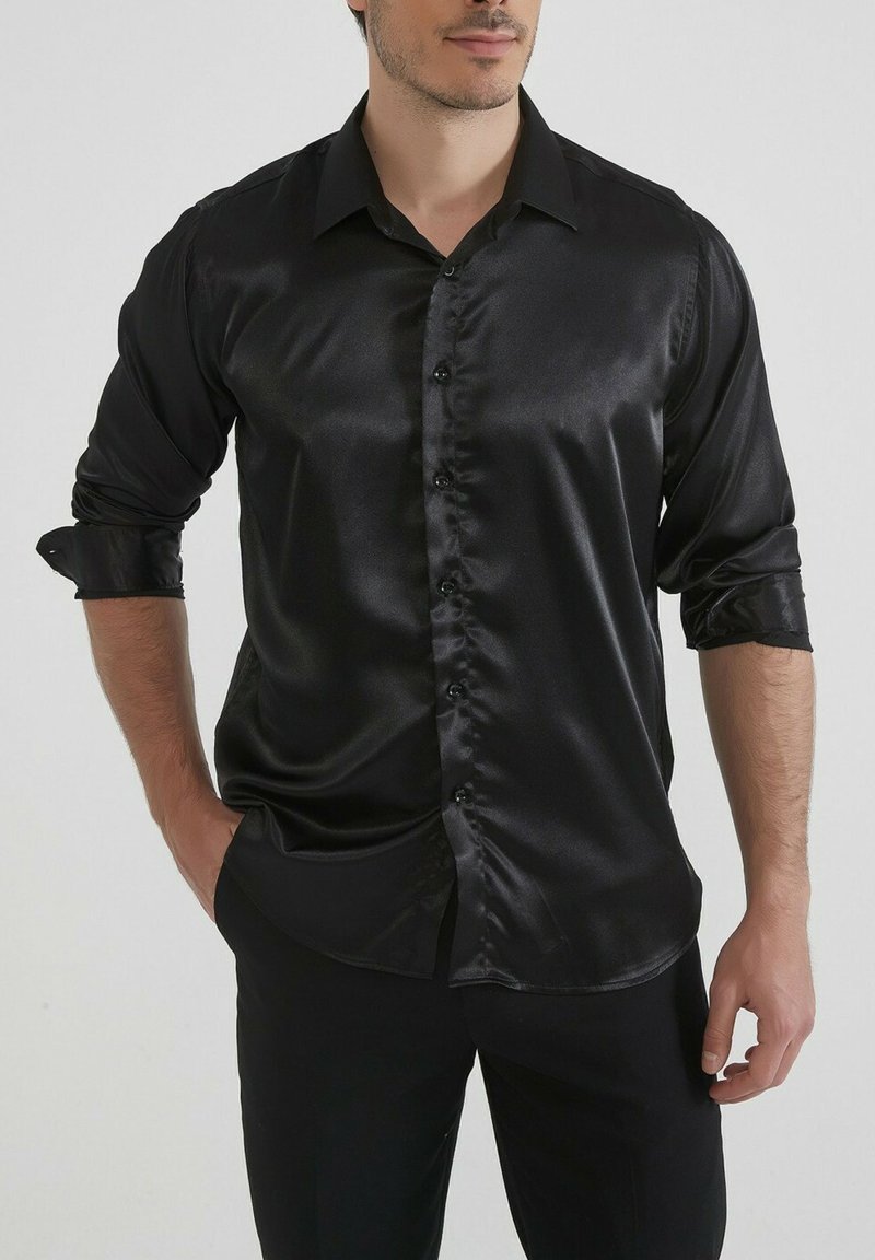 Chemise en satin noir avec un col classique, manches longues retroussées et un design à boutons sur le devant. Texture lisse et coupe ajustée.
