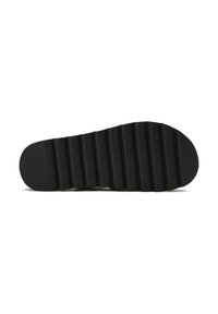 Black shoe sole featuring a ridged pattern with a rounded toe and a flat surface. Made from a flexible material for grip and durability.