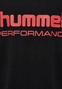 Svart bomullströja med stort rött "hummel"-logotyp och texten "PERFORMANCE". Enkelt design med en mjuk textur.