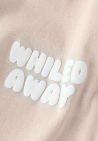 Weiße, abgerundete Blasenbuchstaben, die "WHILED AWAR" auf einem hellbeigen, strukturierten Stoffhintergrund buchstabieren.