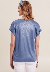 Lichtblauw t-shirt met korte mouwen en een subtiele metallic glans, met opgerolde mouwen en een ontspannen pasvorm. Soepele textuur die zachtjes valt.